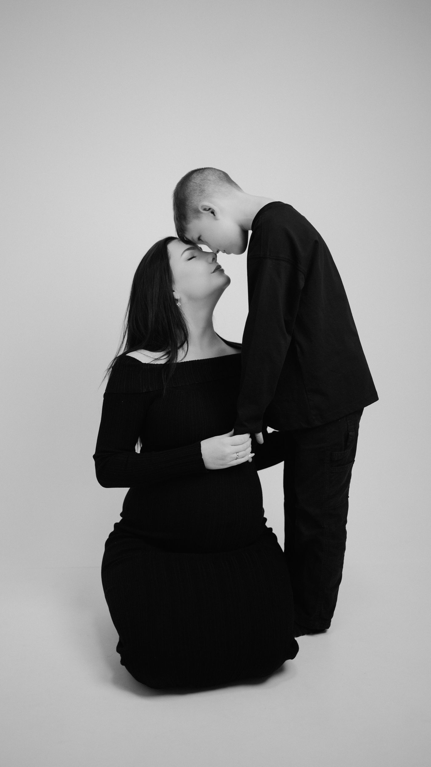 Babybauch-Shooting, Mutter und Sohn Stirn an Stirn, Schwarzweiß